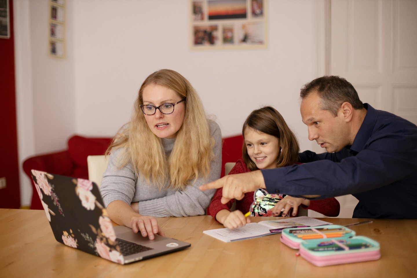 Family uses laptop together at a wooden table.